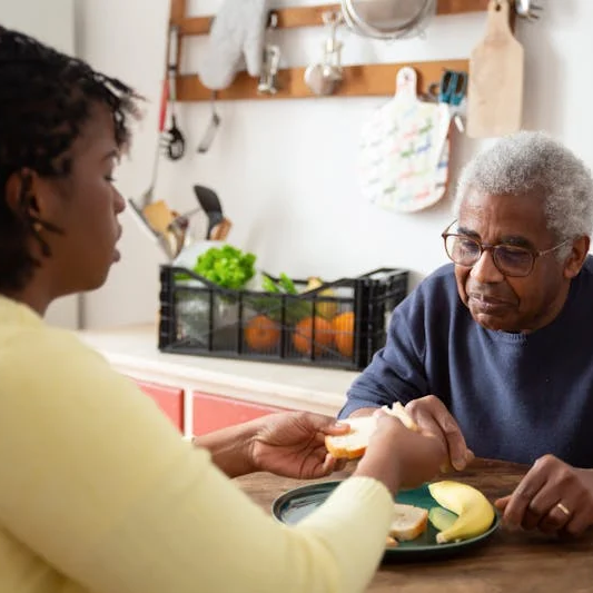 Woman sitting at a table with an older man with a plate of healthy food.
